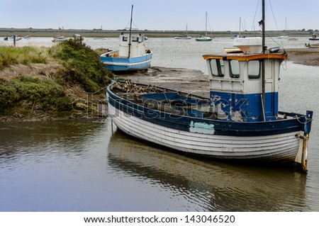 Old wooden fishing boat on mud flats at Brancaster Norfolk England