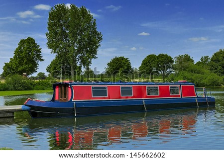 Red narrow boat at a mooring on a summers day in the countryside