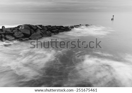 Milky waves splashing over rocks in black and white