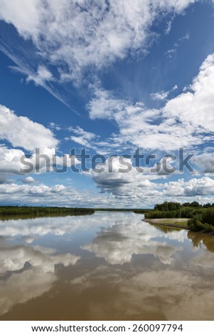 Beautiful summer landscape: view on Kamchatka River, beautiful clouds and reflection in water. Russia, Far East, Kamchatka Peninsula.