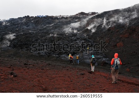 KAMCHATKA, RUSSIA - JULY 27, 2013: Group of tourists hiking on the lava field eruption Tolbachik Volcano on Kamchatka. Russia, Far East, Kamchatka Peninsula.