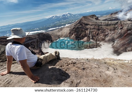KAMCHATKA, RUSSIA - JULY 21, 2013: Tourists in crater of active Gorely Volcano watching at volcanic landscape of Kamchatka Peninsula. Russia, Far East.