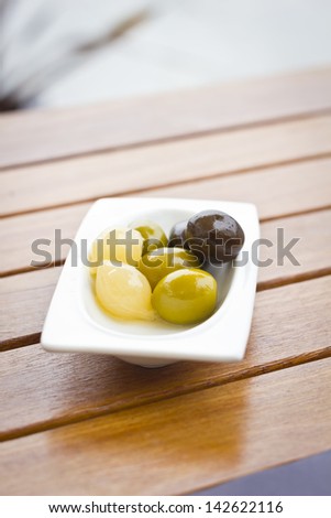 Starter snack of different olives and some small onions or chives.