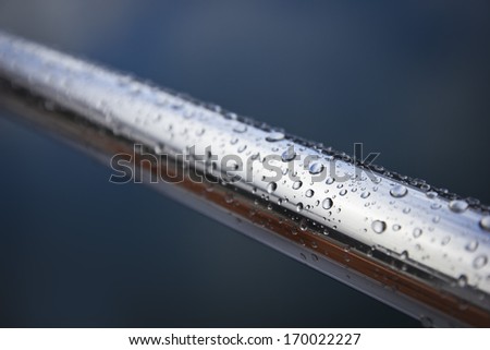 An inox railing full of water drops on a rainy day.