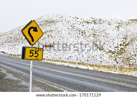 A traffic signal on a snowy landscape, that\'s a dangerous turn.