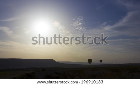 A blue sky with bright sunshine and some balloons silhouettes in Cappadocia, Turkey.
