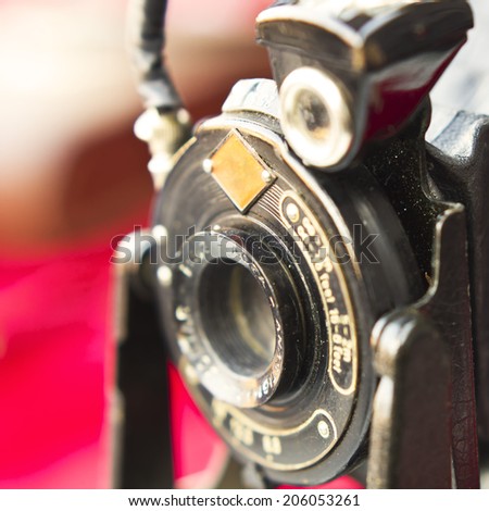 Rusty but beautiful old photographic camera close up still isolated on a red background.