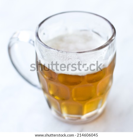 Half full beer jar isolated on a blue white background on a tilt shift filter.