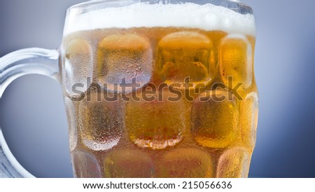 Close up still of an icy full beer jar isolated on a blue background.