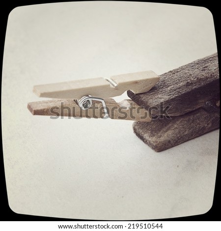 Small clothespin biting an old one on an isolated background and a vintage filter effect.