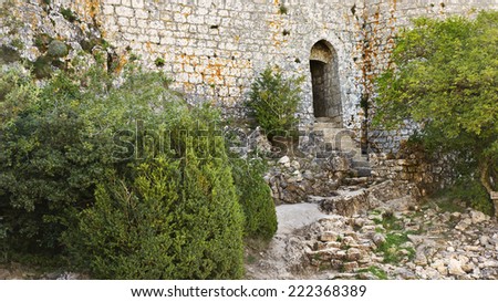 Medieval Peyrepertuse castle entrance in Pyrenees, South France. Old rock and stone wall on a heritage building on a nature path.