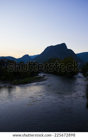 Beautiful blue sky with a river mirror reflection and mountains plus nature trees on a sunset landscape in Pyrenees, Catalonia.