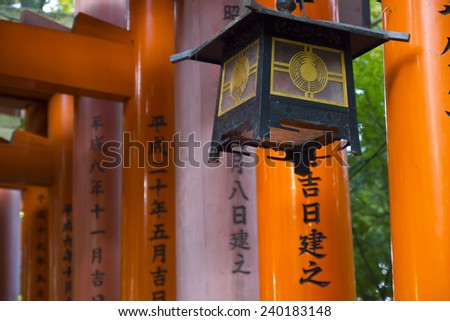 Old metal Japanese lantern on wood tori gates in a shinto shrine in Kyoto, Japan.