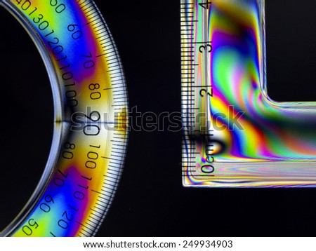 Transparent plastic ruler and draftsman degree on a black background with process polarized filter.