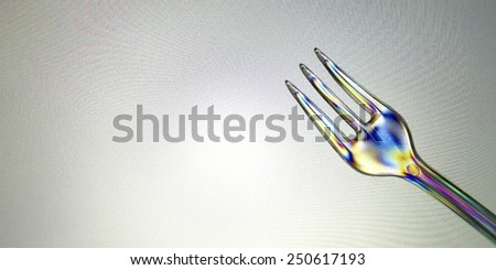 Polarized colorful plastic fork on a grey background on a lighting technique.
