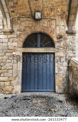 Old blue wood door on an old rock stone wall in Girona, Catalonia.