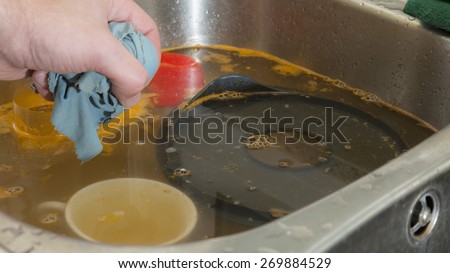 Cleaning dishes, pan and mug in a dirty sink on a domestic kitchen