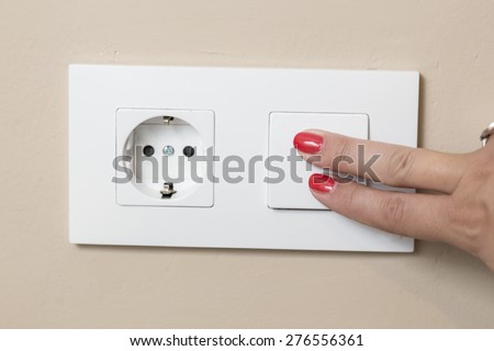 Turn off the light switch.Two girl fingers with red nails painted on a white electricity switch.