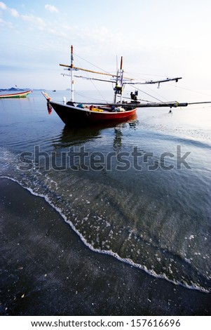 Fishing Boat in The sea.Reflect from sunlight on Ripple sand bubble.wave in foreground.