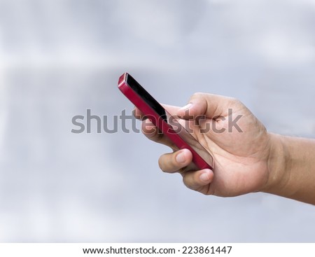 Hand holding red mobile phone. Thumb touch screen.Left side and top side for text area.