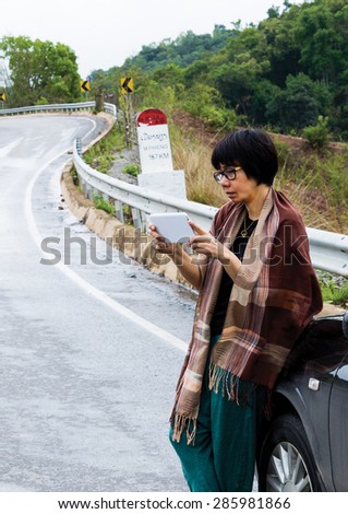On the way in the north of Laos, Woman who is tourist steer a vehicle to the side of the road for check GPS. Look map for distance to Luang Prabang.