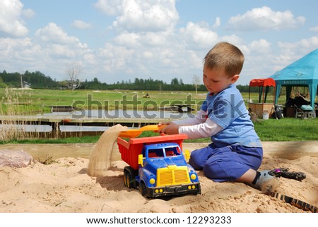 Little boy play in the sand box with color toy car