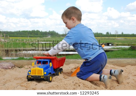 Little boy play in the sand box with color toy car
