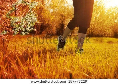 Athlete runner feet running on grass closeup on shoe. Woman fitness sunrise jog workout wellness concept.