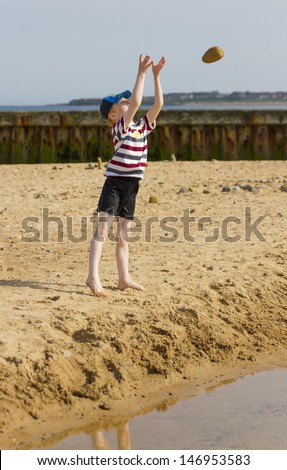 Six year old boy playing at throwing rocks into beach pool.