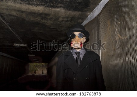 Man dressed in black wearing a rubber horror type mask in a sub-way.