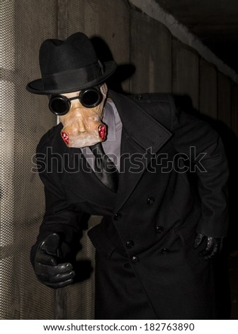 Man dressed in black wearing a rubber horror type mask in a sub-way.