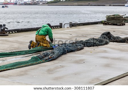 NORTH SHIELDS, TYNESIDE, ENGLAND, MAY 31,2015. On North Shields Fish Quay. Fisherman works to repair fishing nets. May 31. 2015. North Shields, Tyneside, England.UK.