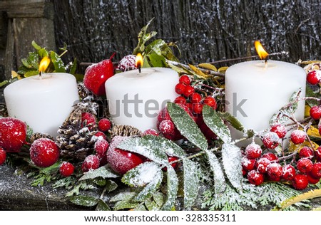 Winter and Christmas candle display with berries and snow.