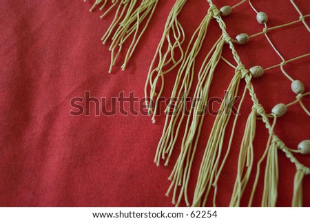 woven beads and tassels on red cloth. Room for Text, or as a background.