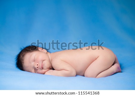 Newborn baby boy sleeps happily on blue blankets
