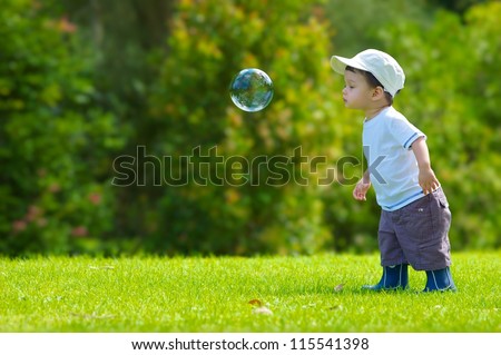Cute Boy Plays With A Giant Bubble Outside In The Park