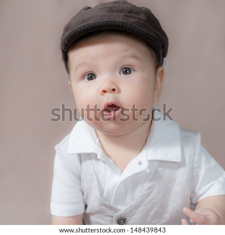 5 month old cute Asian baby boy dressed up, wearing a hat and making funny faces. Part of a series of square format images with different expressions
