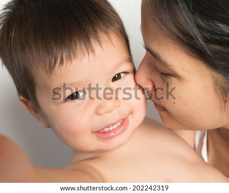 18 month old mixed race Asian boy plays happily with his Asian mom. Looking at camera