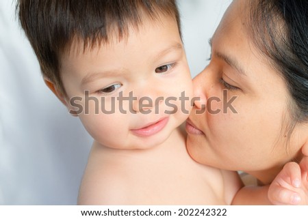 18 month old mixed race Asian boy plays happily with his Asian mom
