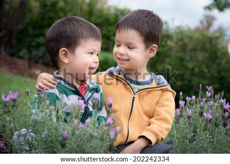 2 brothers play happily together in a suburban garden