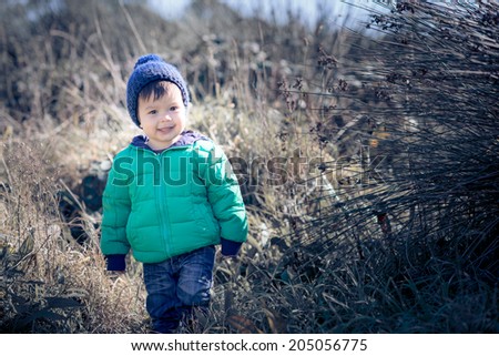 1 year old Asian Caucasian boy in a green winter jacket on a sunny cold winter day