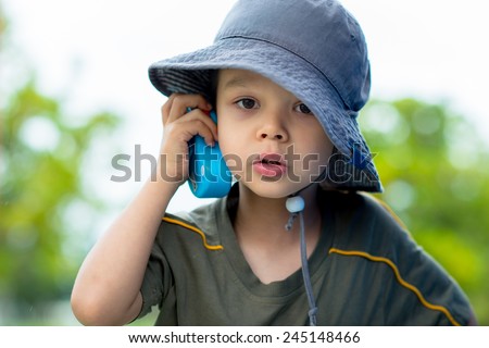 Cute 4 year old mixed race Asian Caucasian boy plays outside in a playground with a toy walkie talkie radio