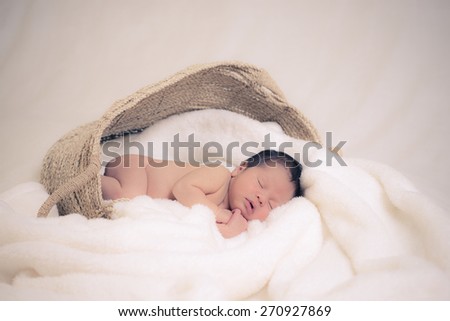 5 day old mixed race Asian Caucasian newborn baby boy sleeps peacefully on thick soft blankets.