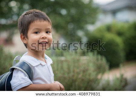 Cute 3 year old mixed race Asian Caucasian boy confidently leaves home for his first day at preschool