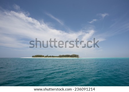 Idyllic paradise and dream holiday island in the Indian Ocean with turquoise and aqua ocean and a deep blue sea with wispy clouds surrounded by underwater coral reefs and white sandy beaches