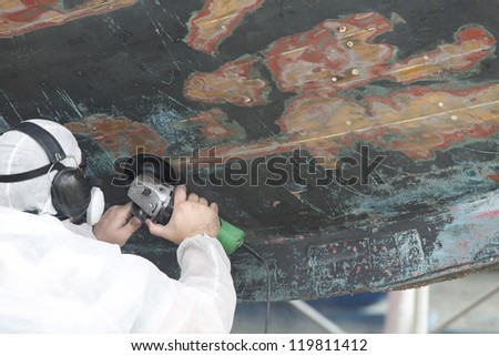 Boat Hull repairs/ a large wooden boat\'s hull getting sanded in preparation for anti foul paint being applied