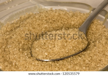 Sugar and teaspoon/ Brown sugar in a glass bowl with a teaspoon, shot in macro