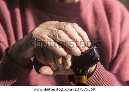 Elderly Woman\'s Hands/ an elderly widow rests her hands on her walking cane