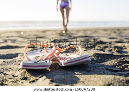 Beach Flip-Flops/ a woman swimmer leaves her jandals in the sand to go for a swim