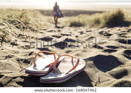 Dune Flip- Flops/ a woman leaves her jandals at the top of dunes to go for a beach swim